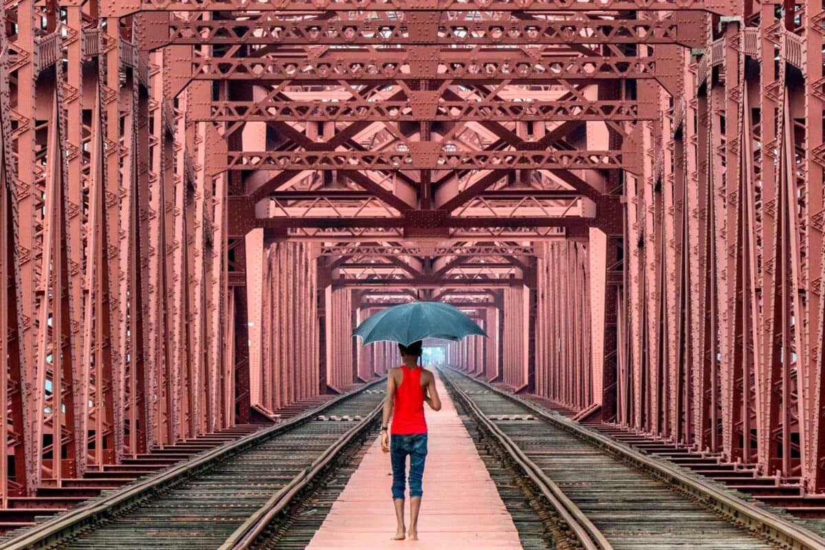 Een man met een paraplu loopt over een spoorbrug