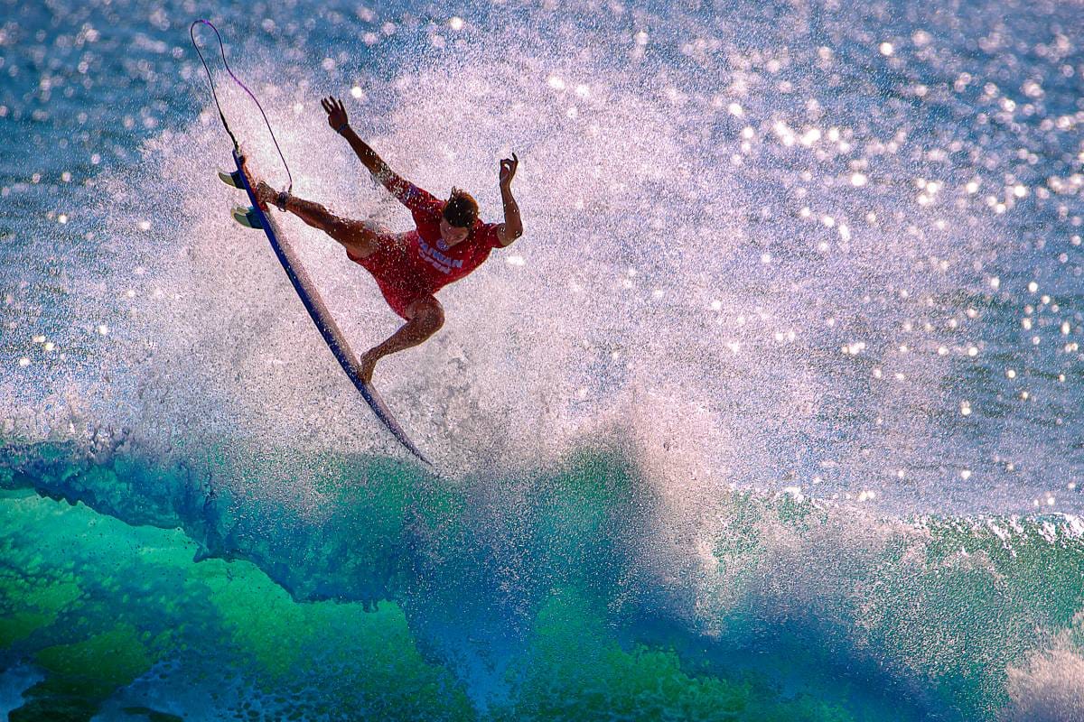 Een surfer maakt een hoge sprong in de golven