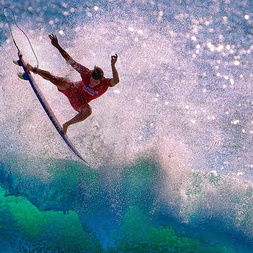 Een surfer maakt een hoge sprong in de golven