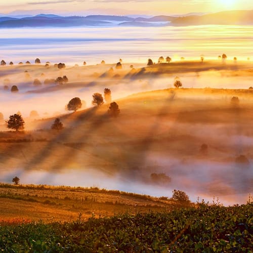 Een ochtendmist hangt over een heuvelachtig landschap in Myanmar