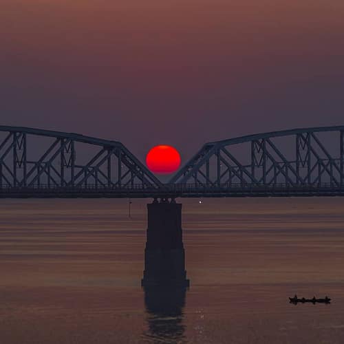 Zonsondergang met rode zon bij brug