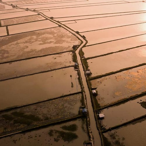 Landschap met onder water gelopen akkers vanuit de lucht gezien bij zonsondergang