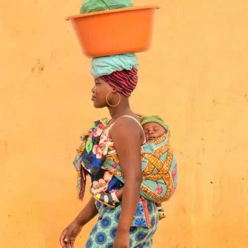 Miranda-Acacio-Gregory-Escande-500x500 Een Afrikaanse vrouw met een baby op haar rug loopt langs een gele muur
