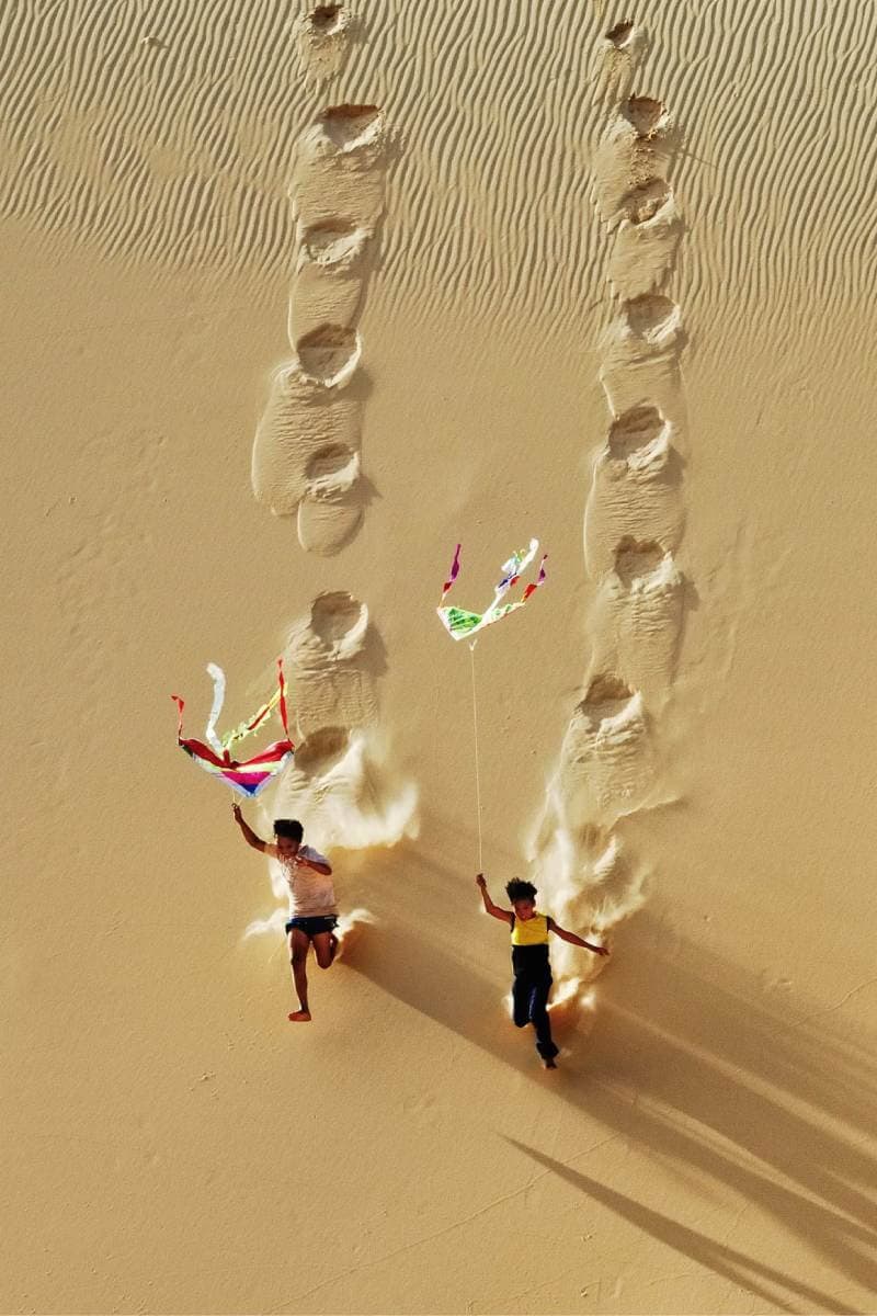Kinderen spelen met een vlieger in duinen
